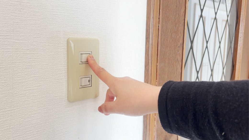 電気のスイッチに触れる手