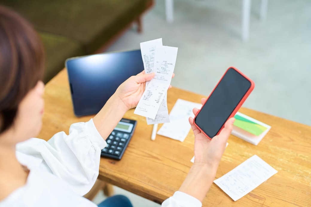 レシートとスマホを持つ女性