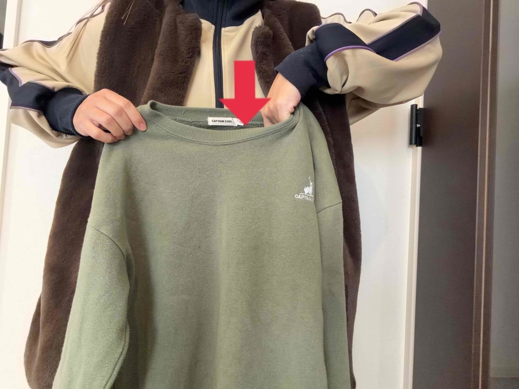 服の首元の上から手を入れようとしているところ