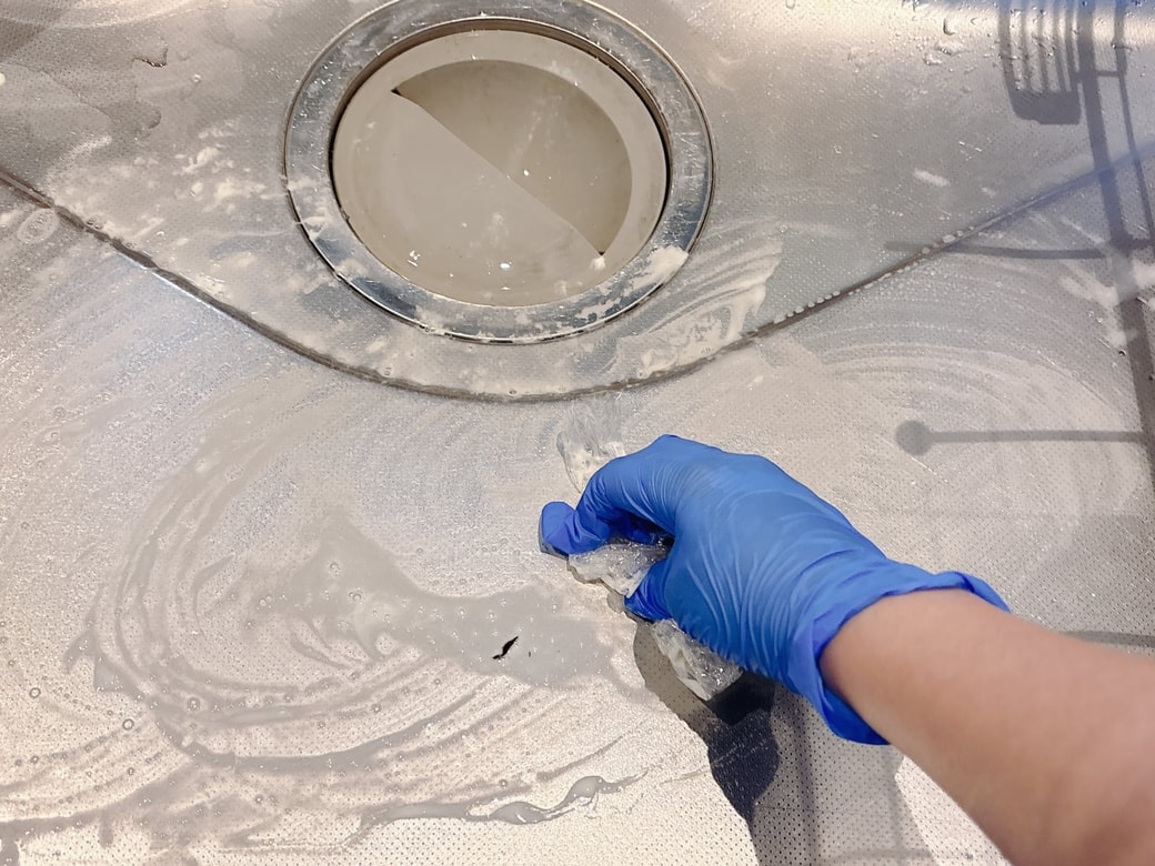 キッチンシンクの汚れをこすり落とす