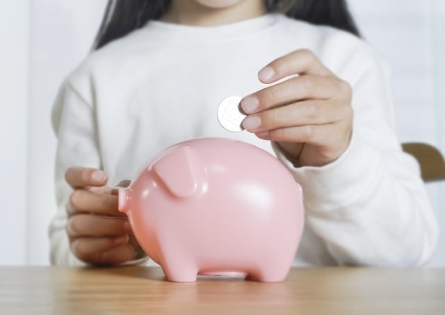 貯金箱にお金を入れる子ども