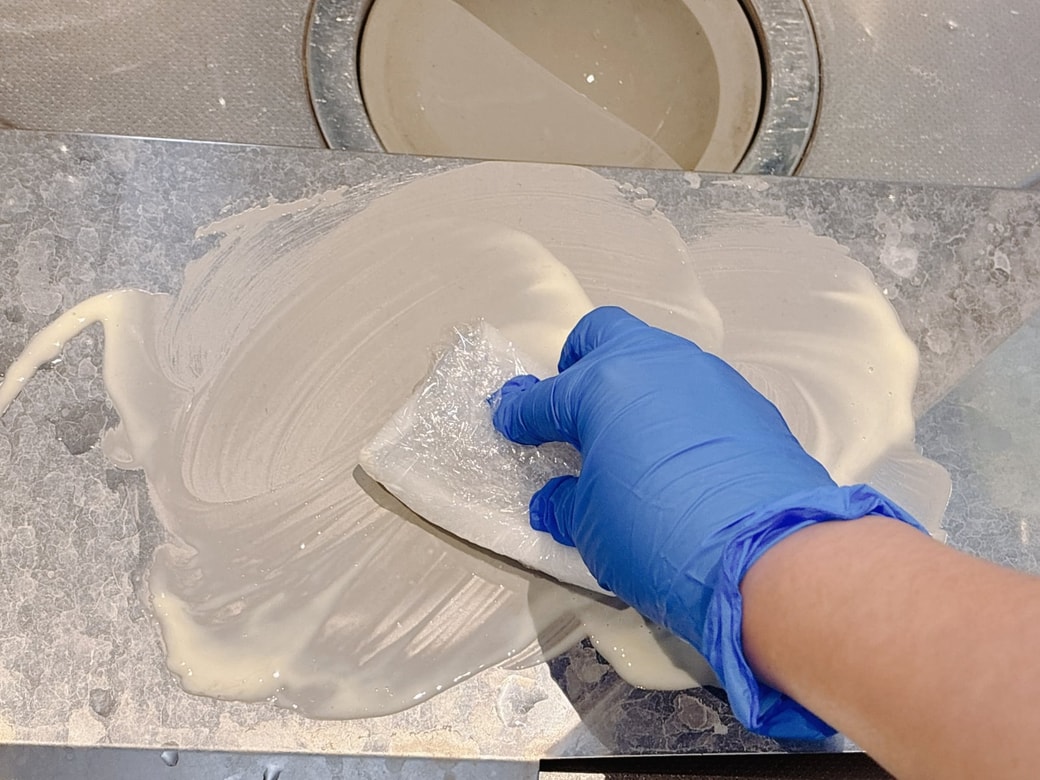 水受け皿の水アカをこすり落とす