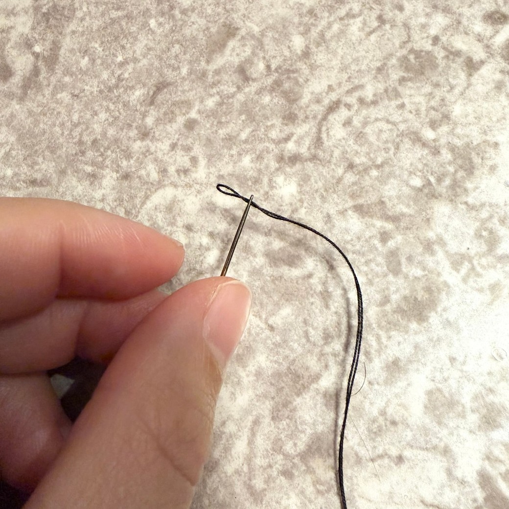 輪を針に通しているところ