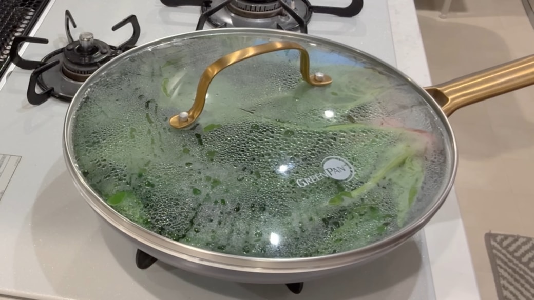 フライパンでほうれん草を蒸している人