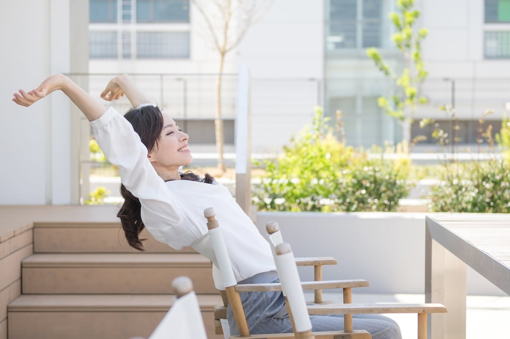 座って背伸びをする女性