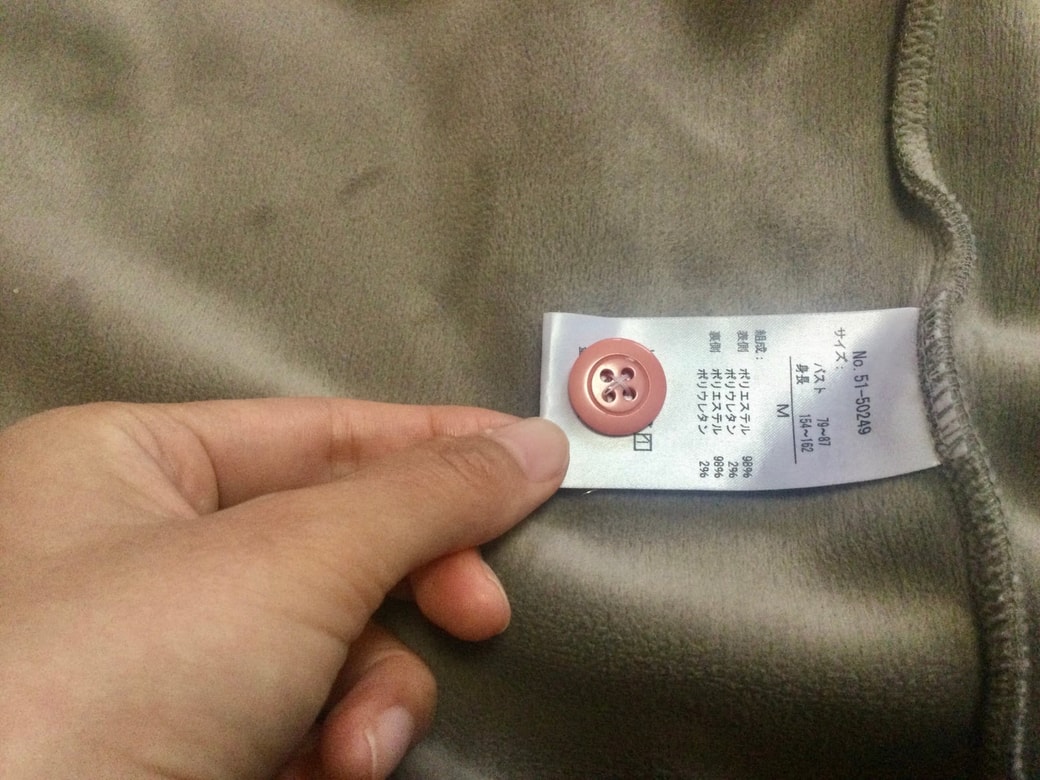 服の洗濯タグにボタンを縫い付ける