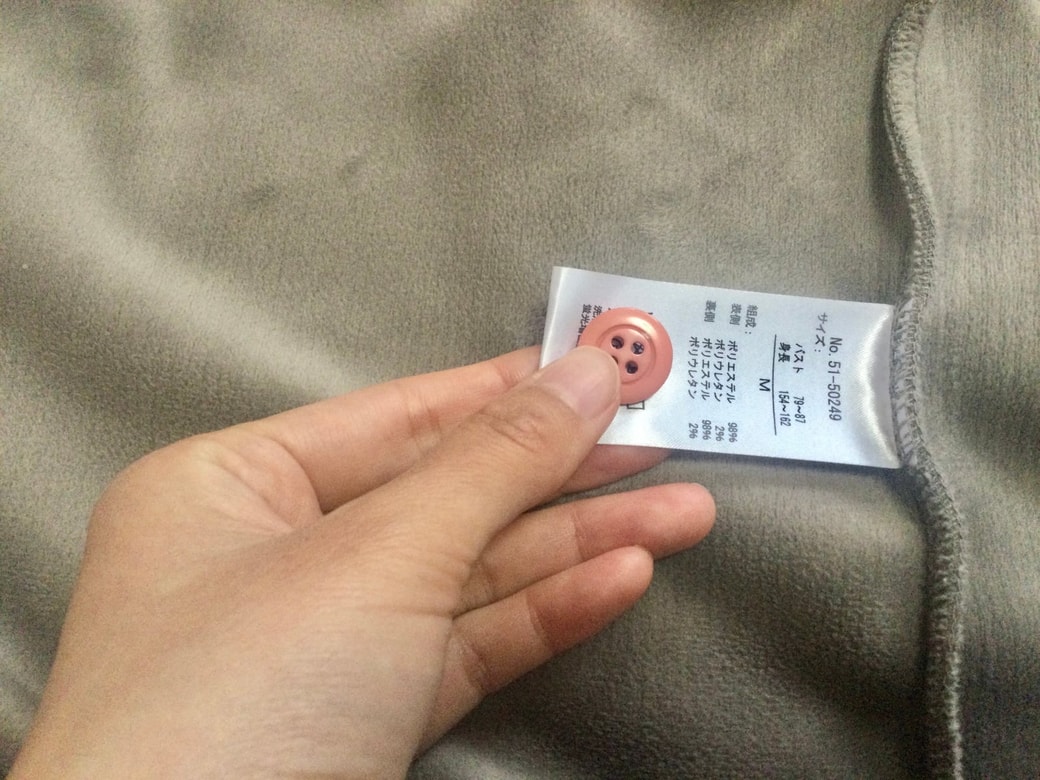 服の洗濯タグにボタンを縫い付ける