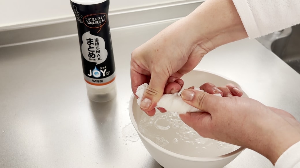 洗剤を含ませたクロスを絞る