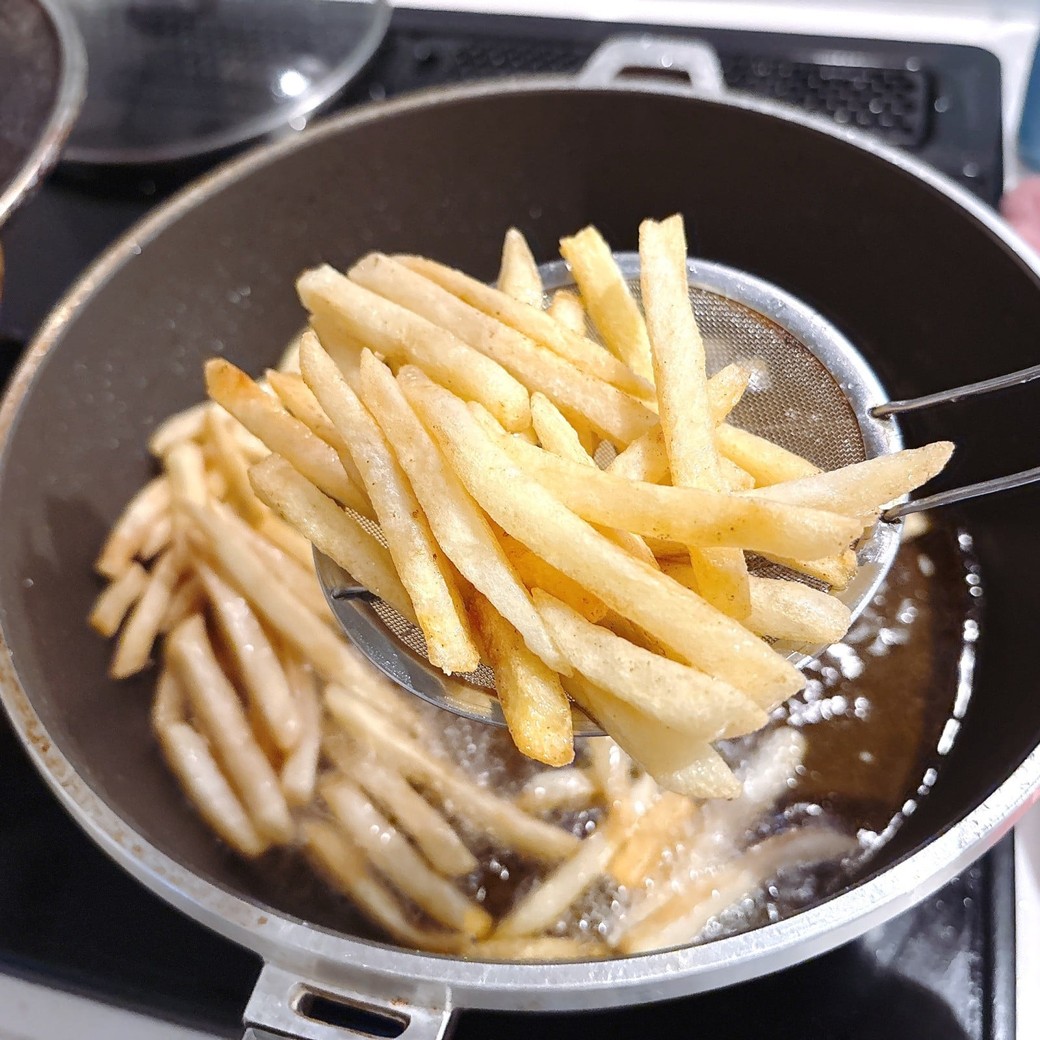 冷凍のフライドポテトを油で揚げる