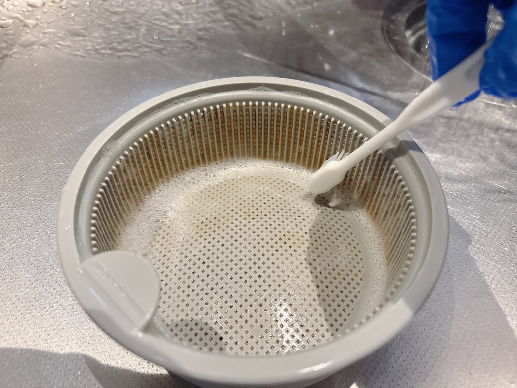 歯ブラシでゴミ受けをこする