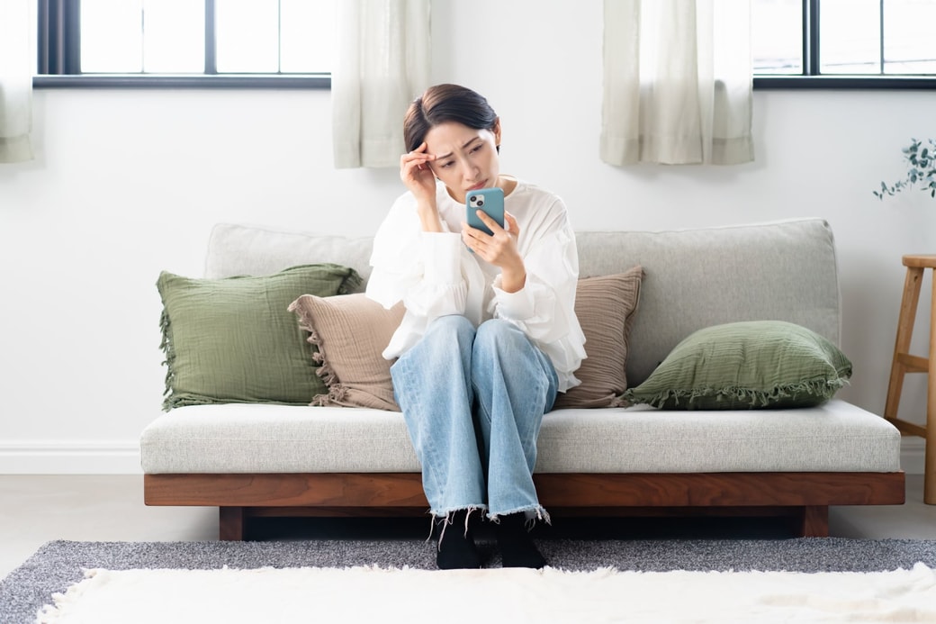 スマホを見て悩む女性