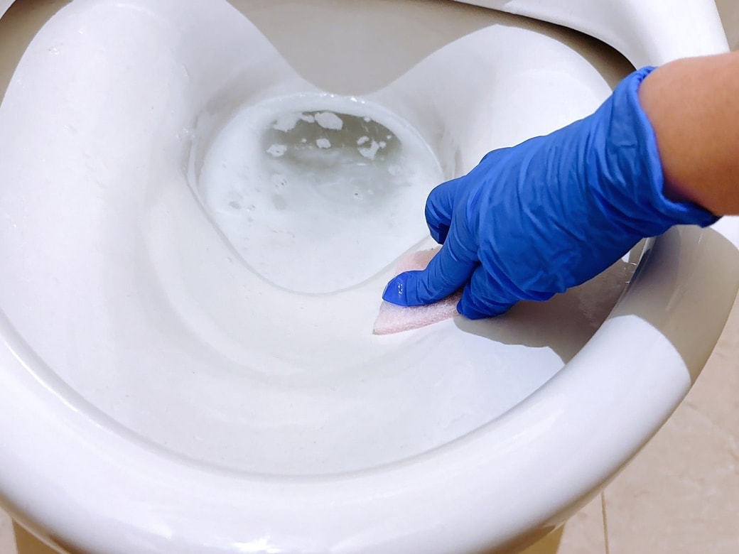 手袋をはめて、洗剤パッドで便器を掃除する