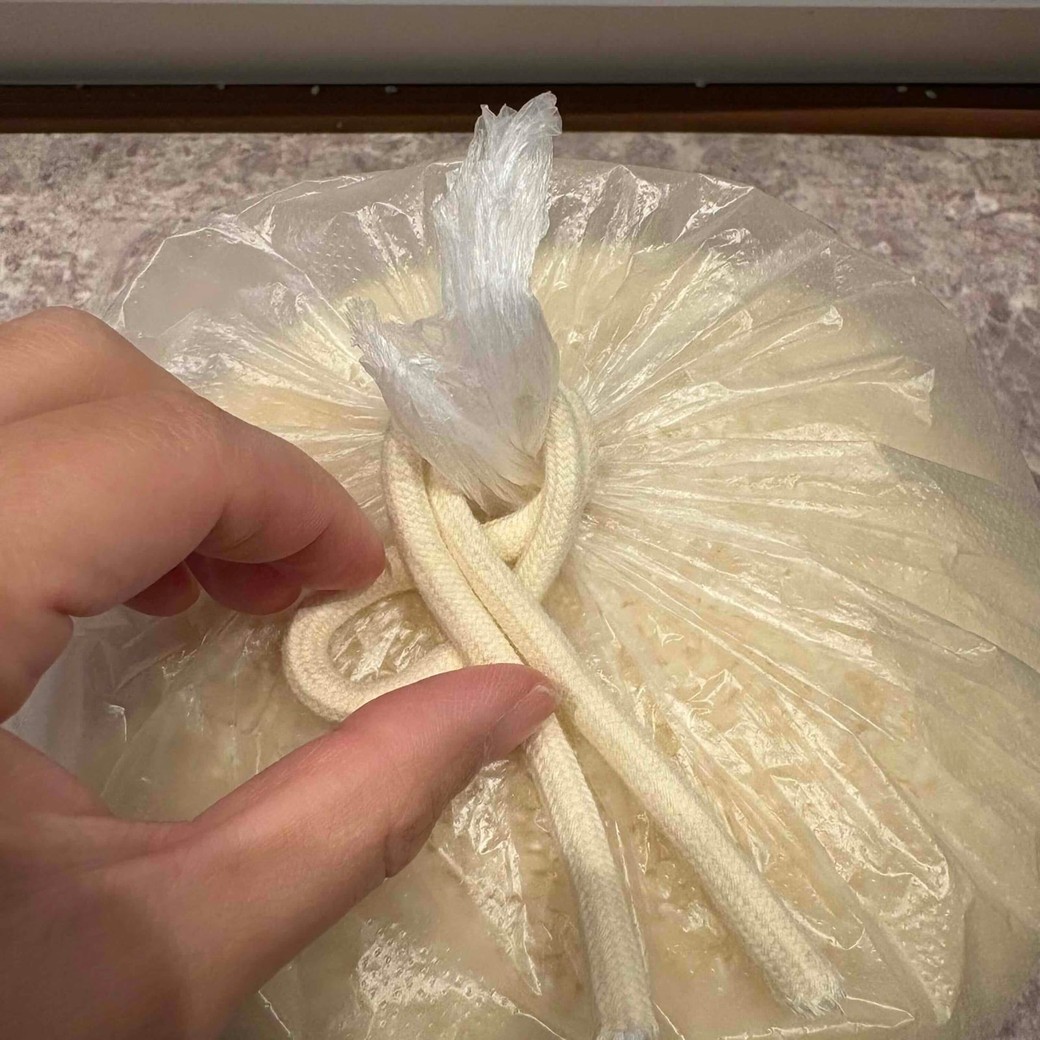 袋の口に紐を巻き付けているところ