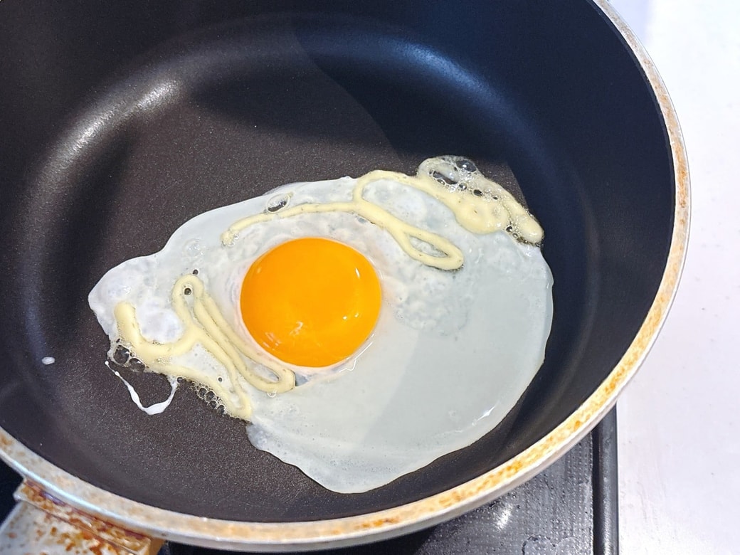 フライパンに卵を割り入れる