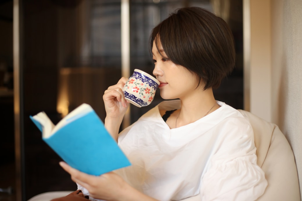 コーヒーを飲みながら読書する女性