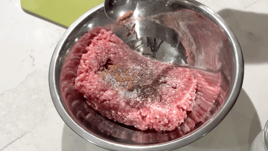 ボウルでひき肉などを混ぜ合わせる人