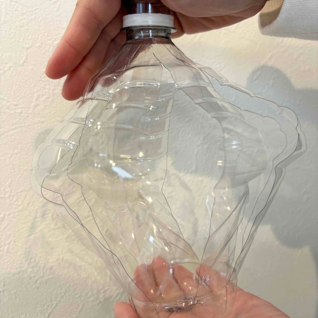 切れ込みを入れたペットボトルをつぶしているところ
