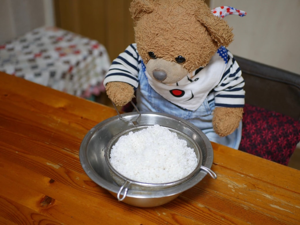 研いだ米をザルにあげる