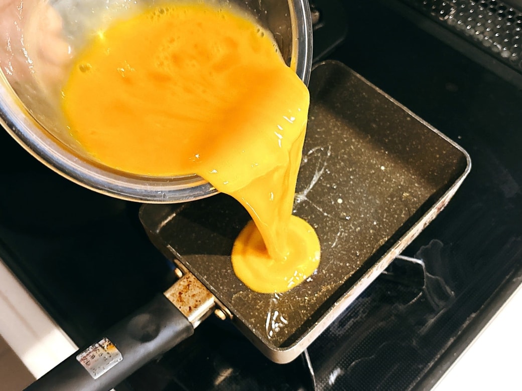 玉子焼き器に卵液を流す