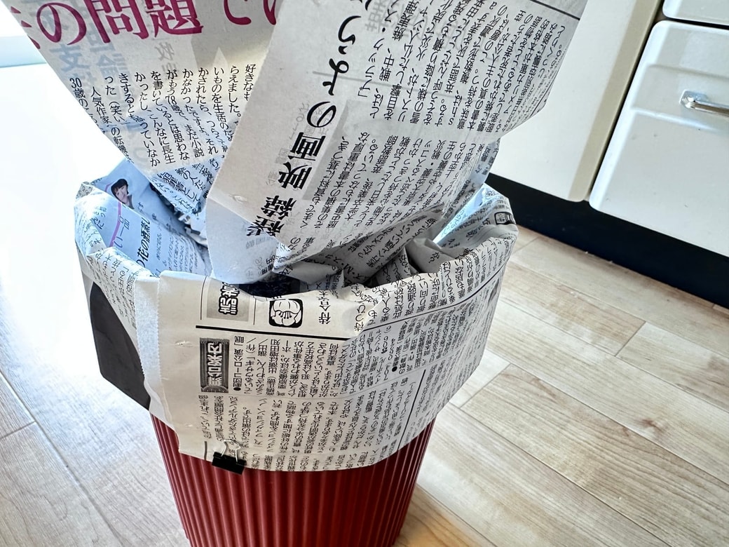 新聞紙をゴミ箱の中に入れる
