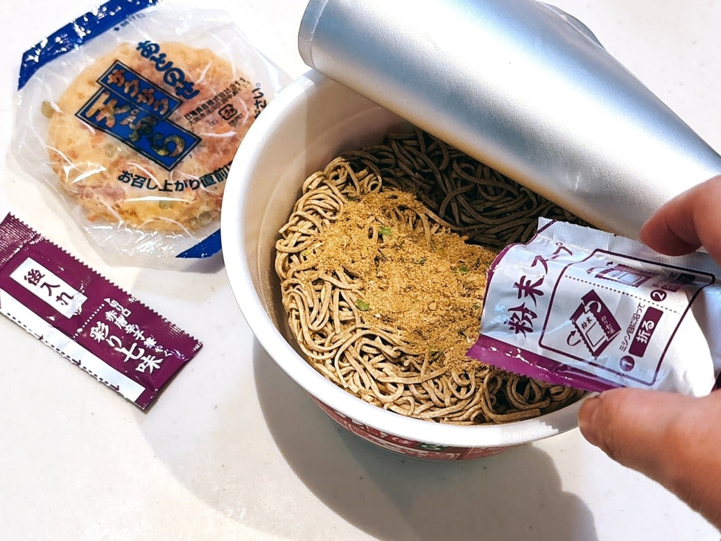 どん兵衛に粉末スープと卵を割り入れる