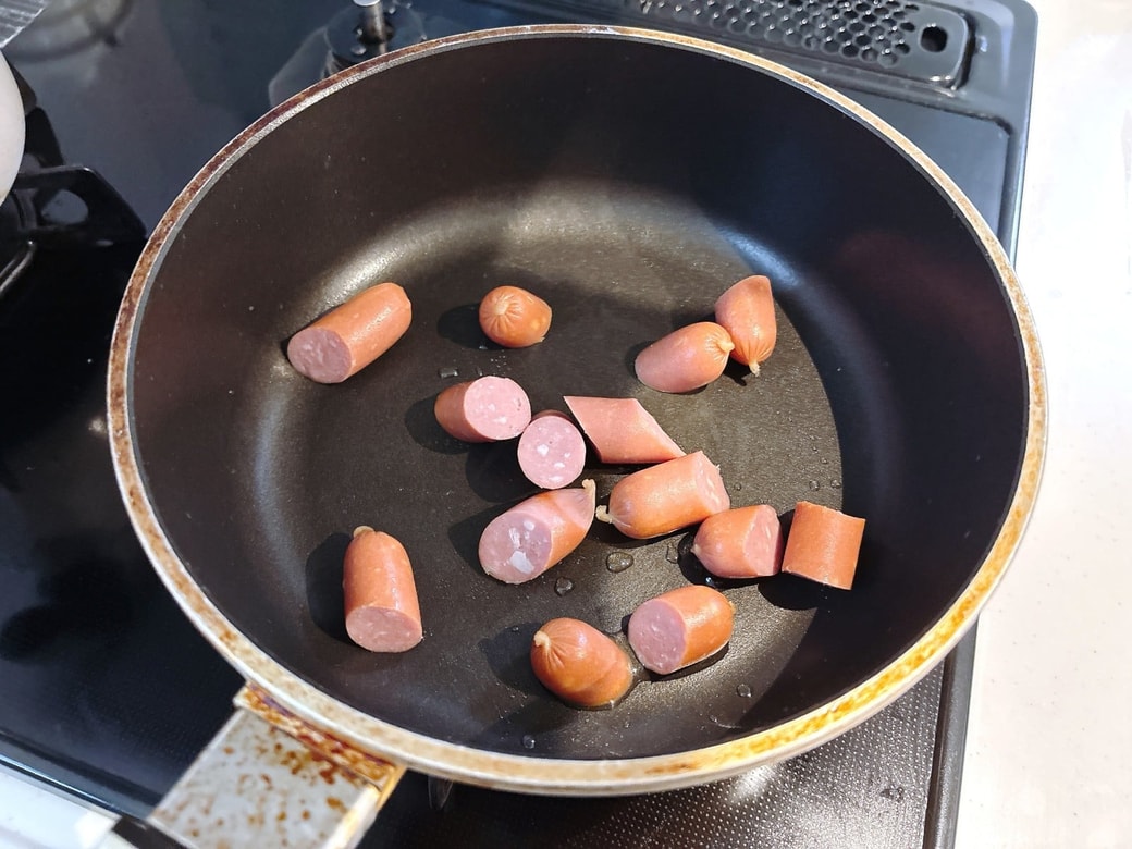 食べやすい大きさにカットしたウインナーをフライパンで焼く