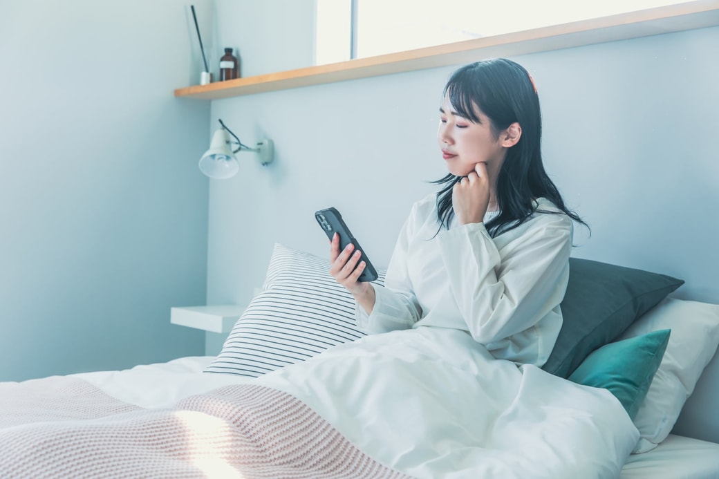 ベッドでスマホを見る女性