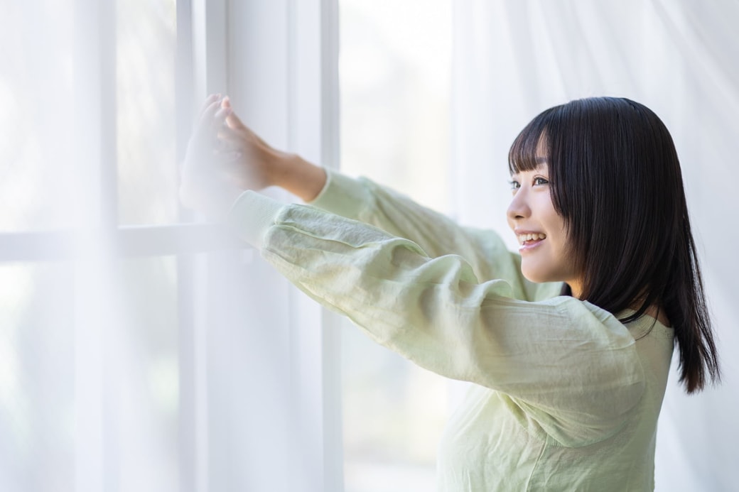 カーテンを開ける女性