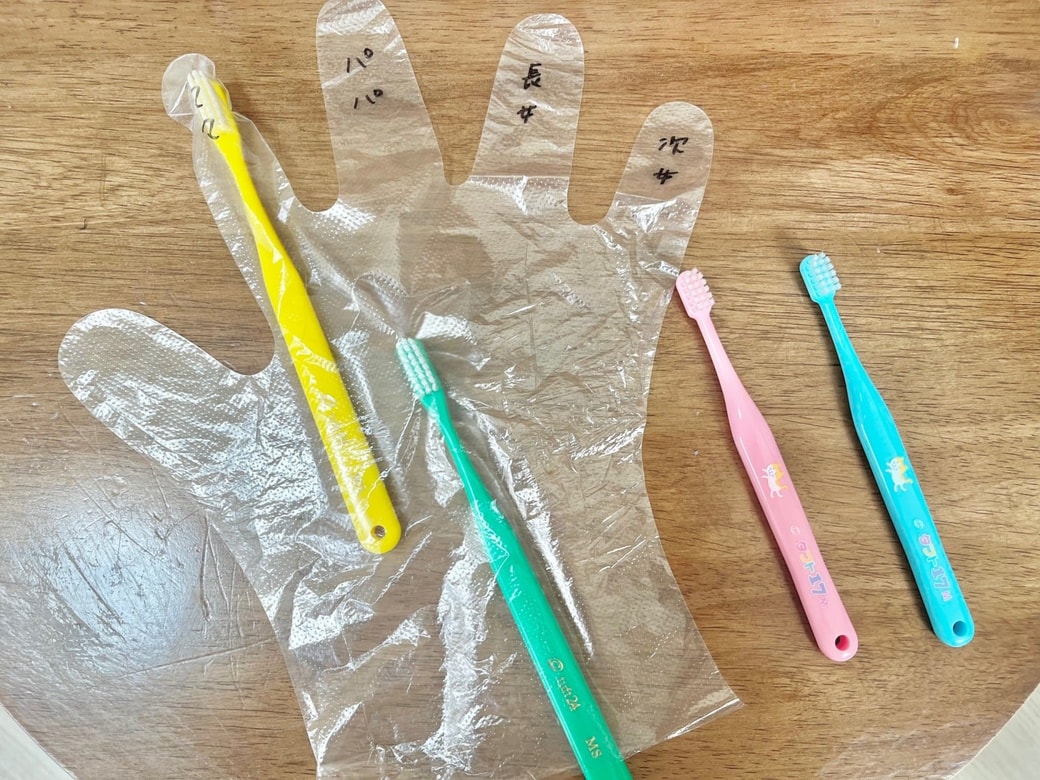 ビニール手袋で家族分の歯ブラシを包める