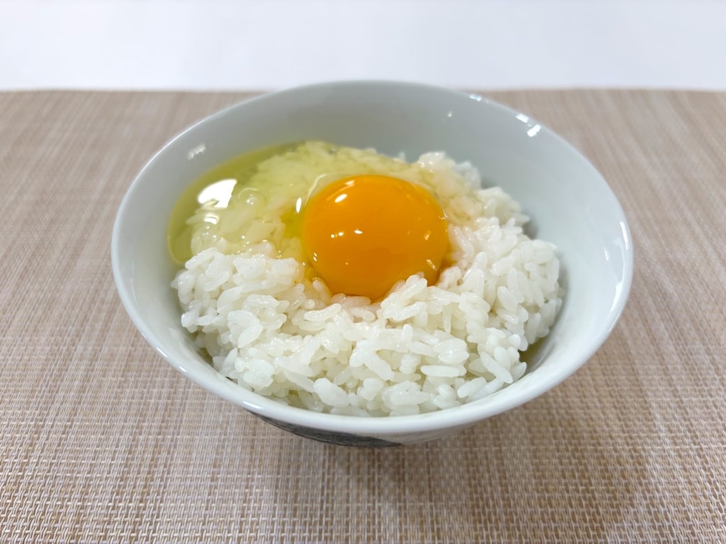 温かいご飯の上に卵を割り入れる