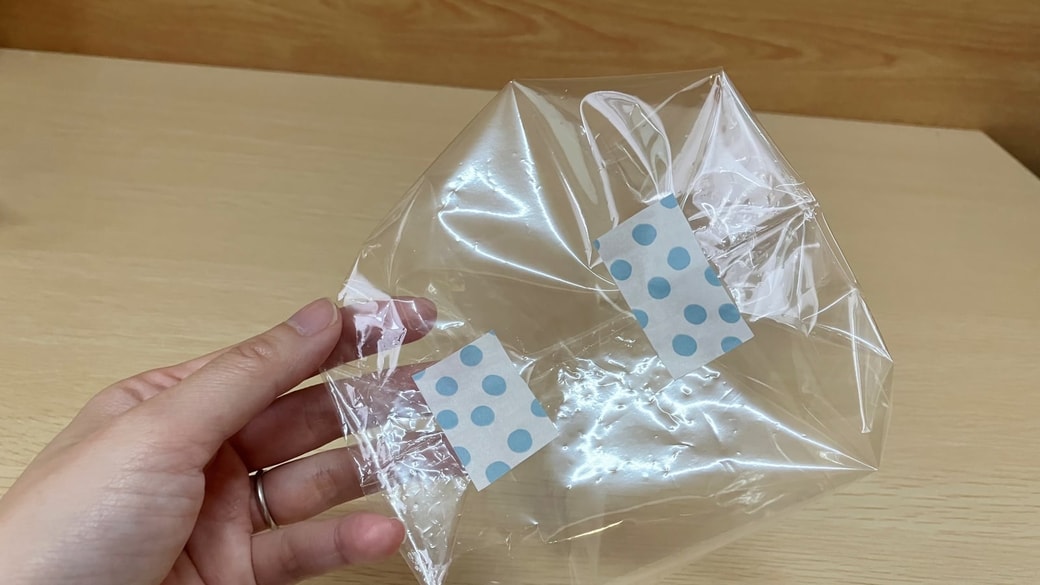 反対側も三角に折ってテープを貼る様子