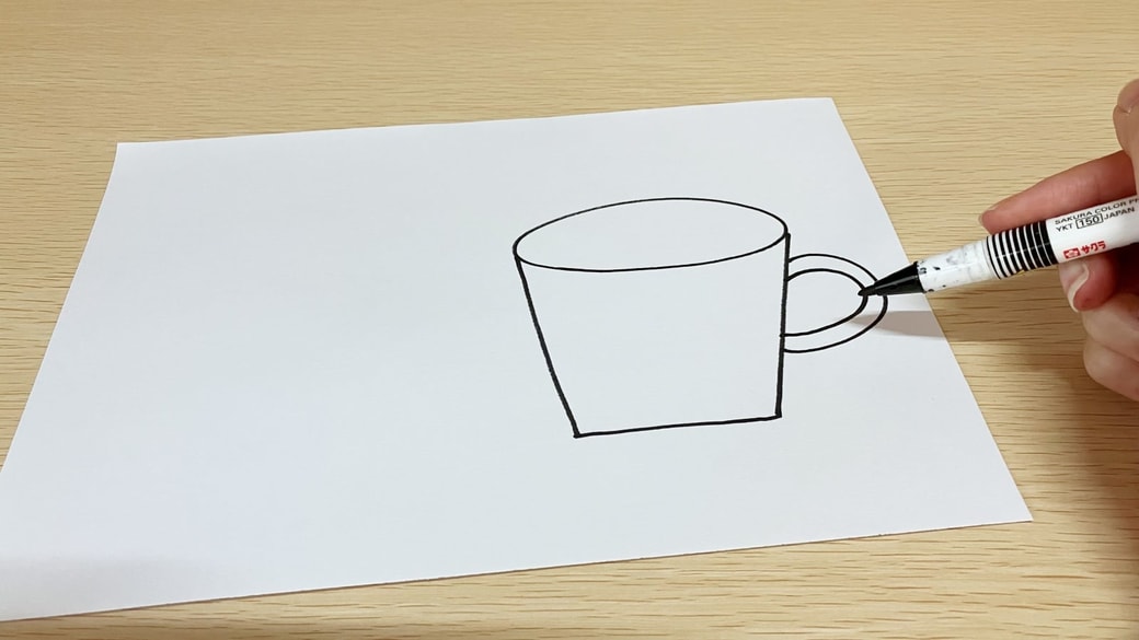 画用紙に持ち手つきのカップを描く様子