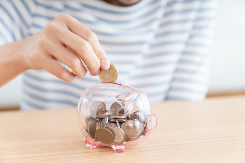 貯金箱にお金を入れる女性