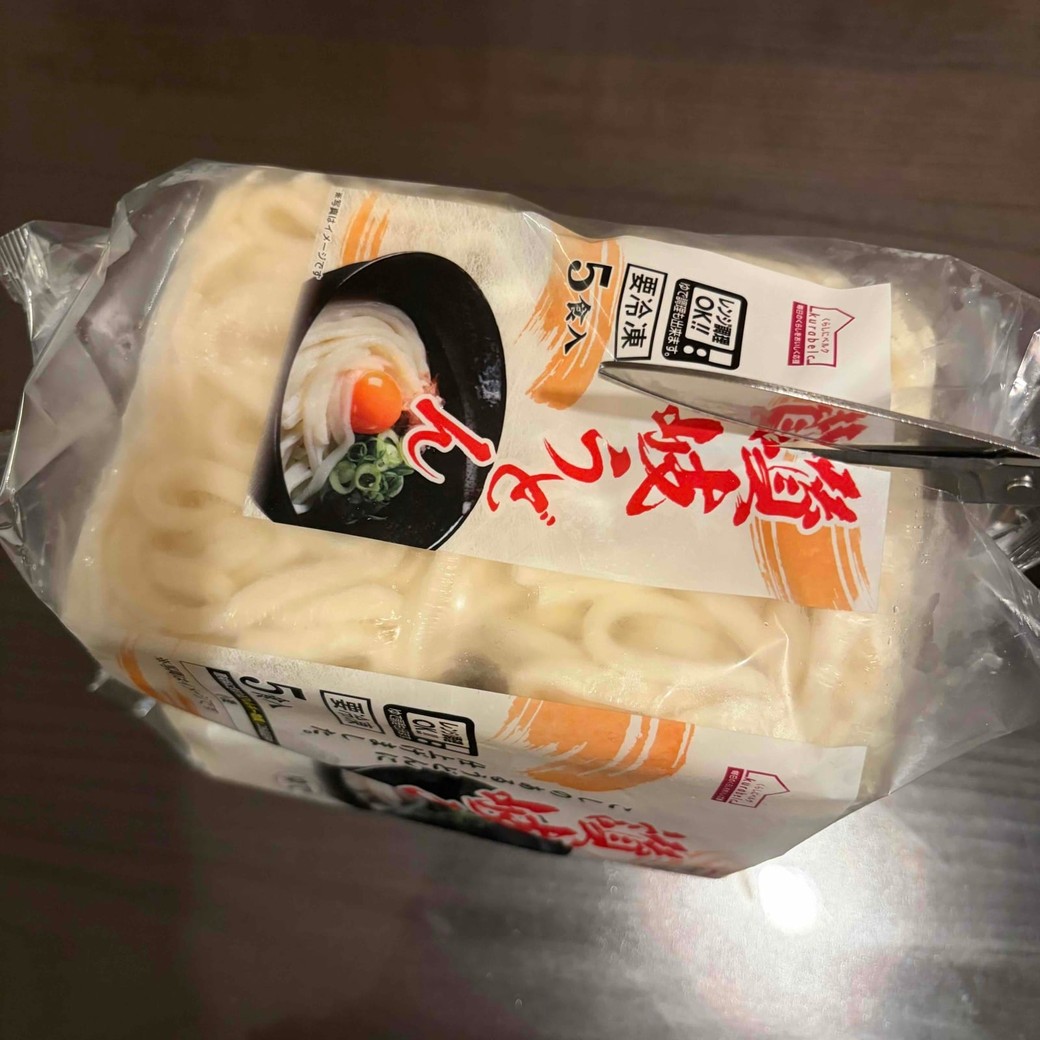 冷凍うどんの袋の横部分を切っているところ
