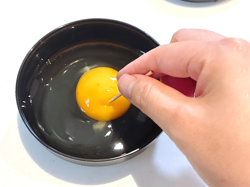 割り入れた卵に、つまようじで穴をあける