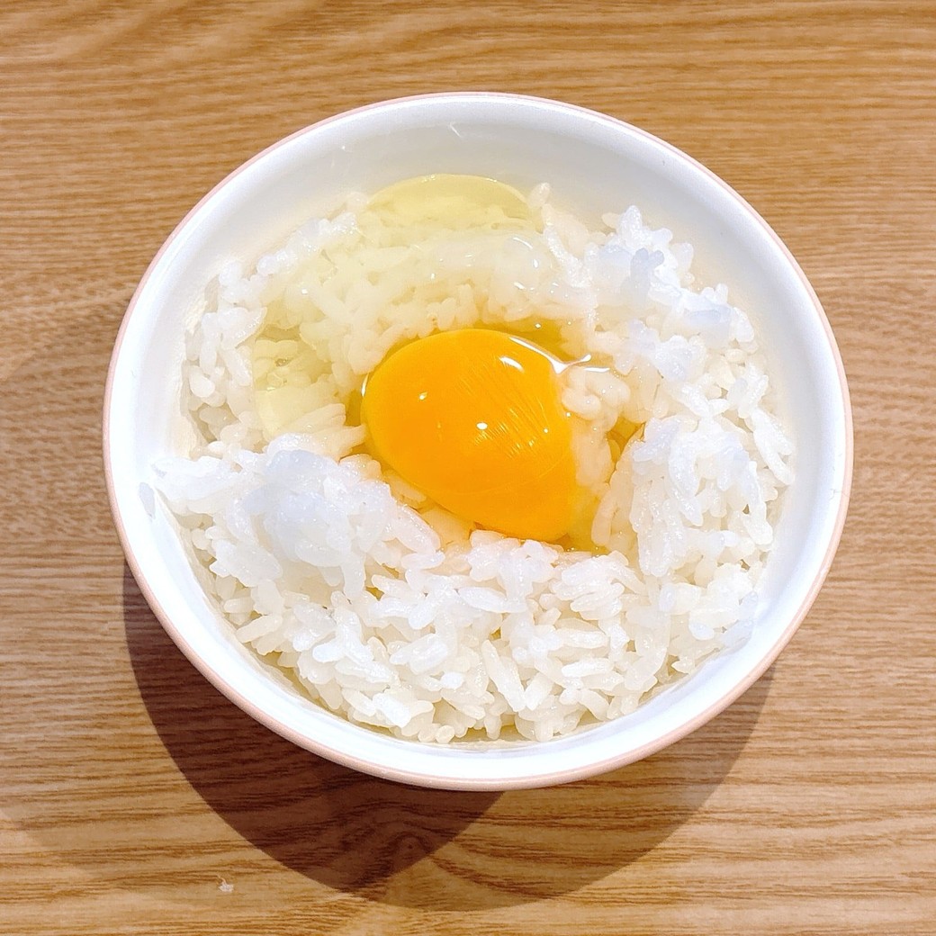 ごはんに卵を割り入れる