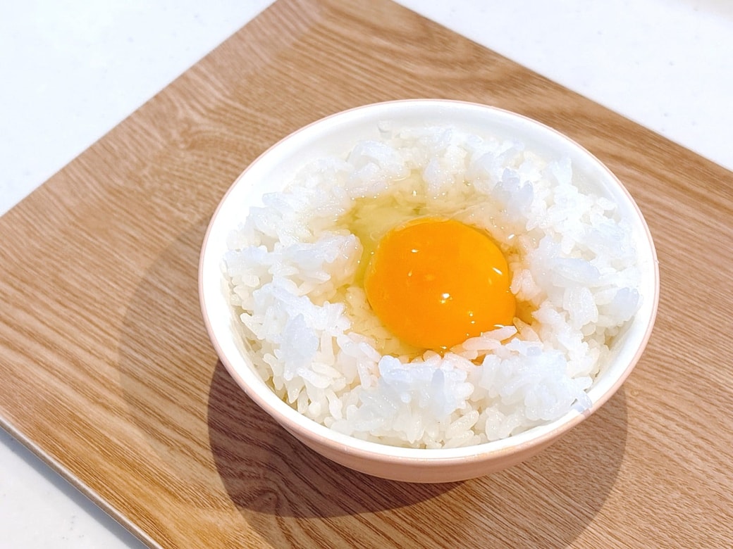 ごはんに卵を割り入れる