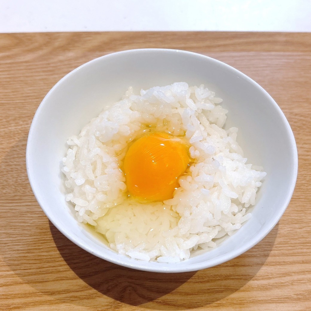ごはんを茶碗に盛り、卵を割り入れる