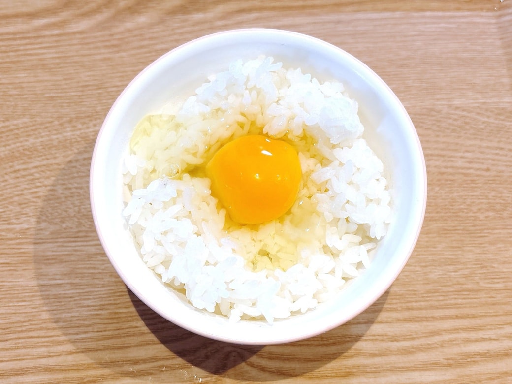 ごはんを茶碗に盛り、卵を割り入れる