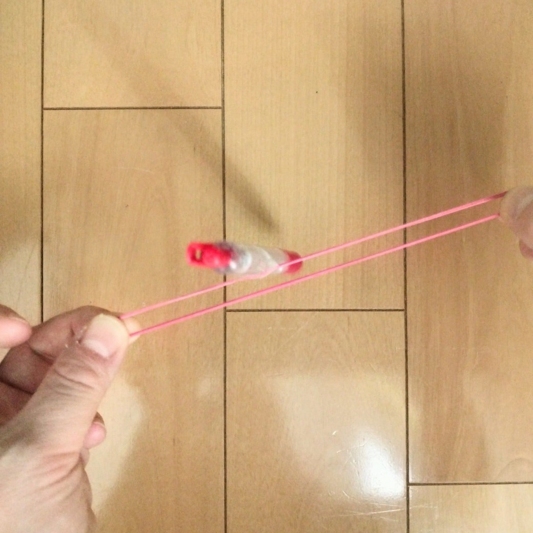 ボールペンに貼りつけた輪ゴムを引っ張る人