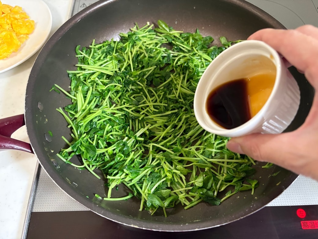 豆苗を炒めて調味料を加える