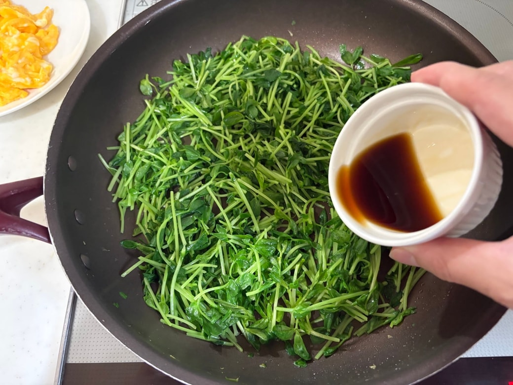 豆苗を炒めて調味料を加える