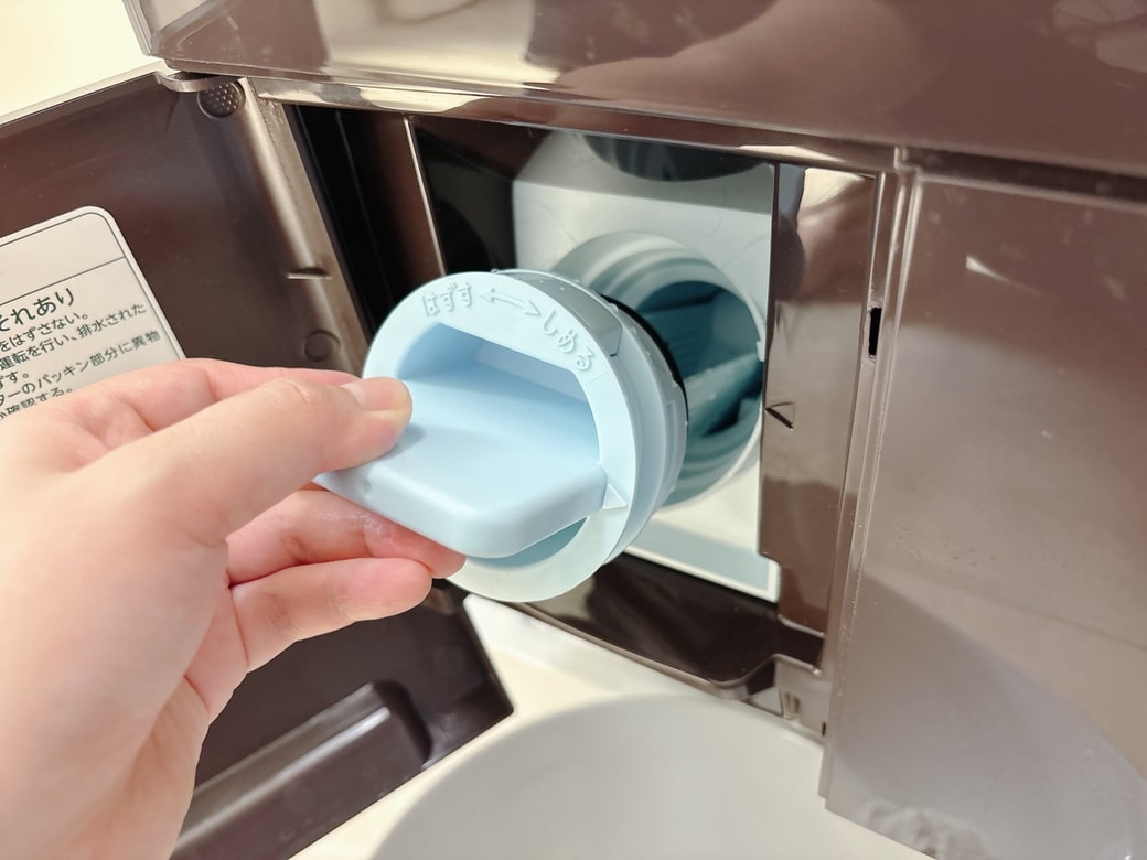 桶を置き、ふたを開けて排水フィルターを取り除く