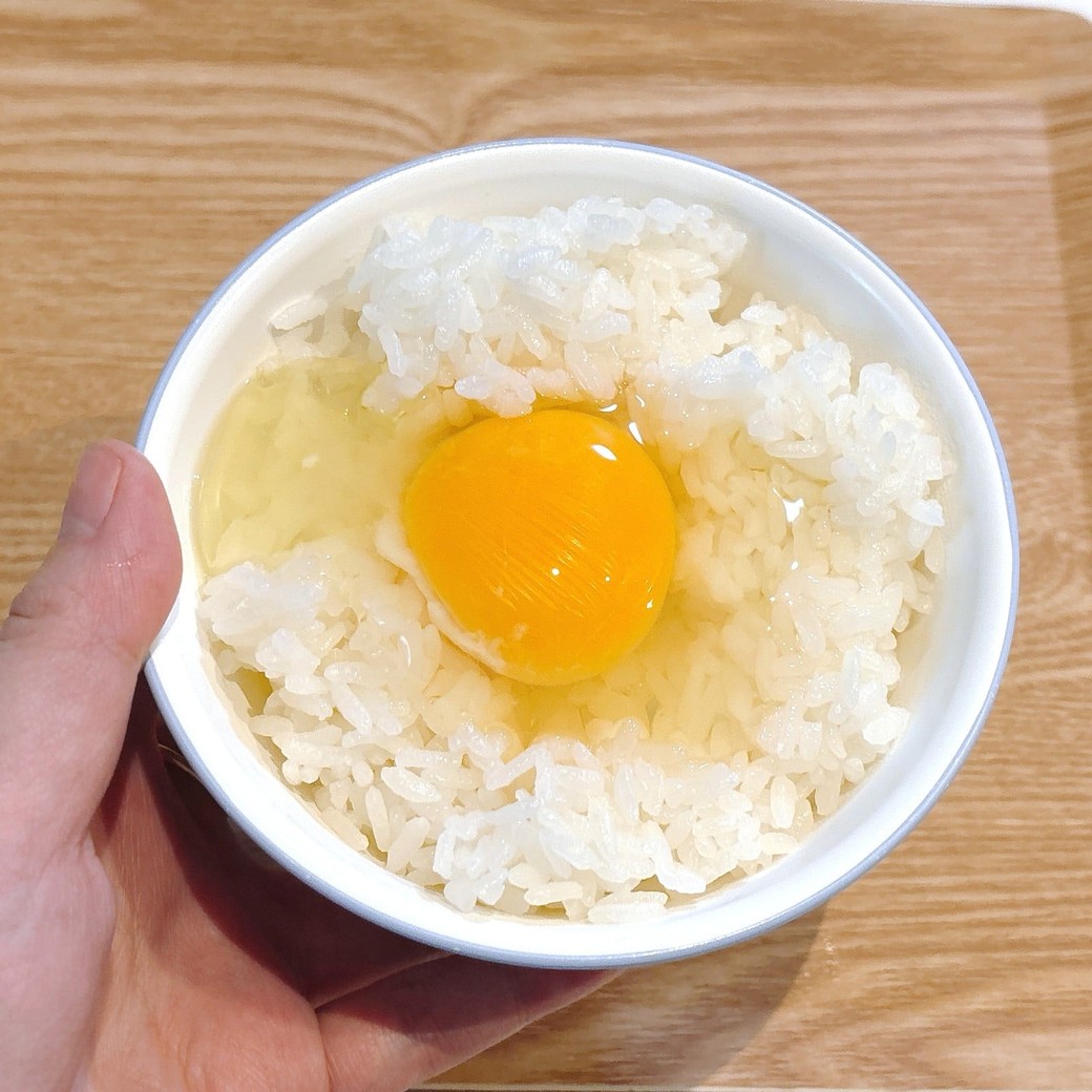 ごはんに卵を割り入れる