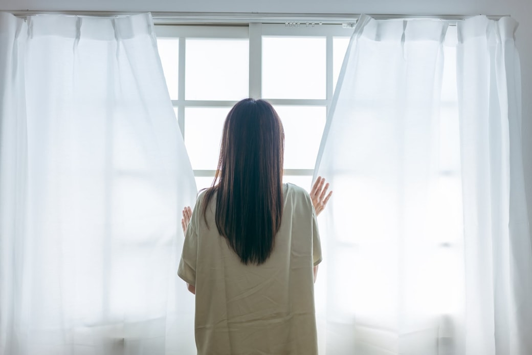 カーテンを閉める女性