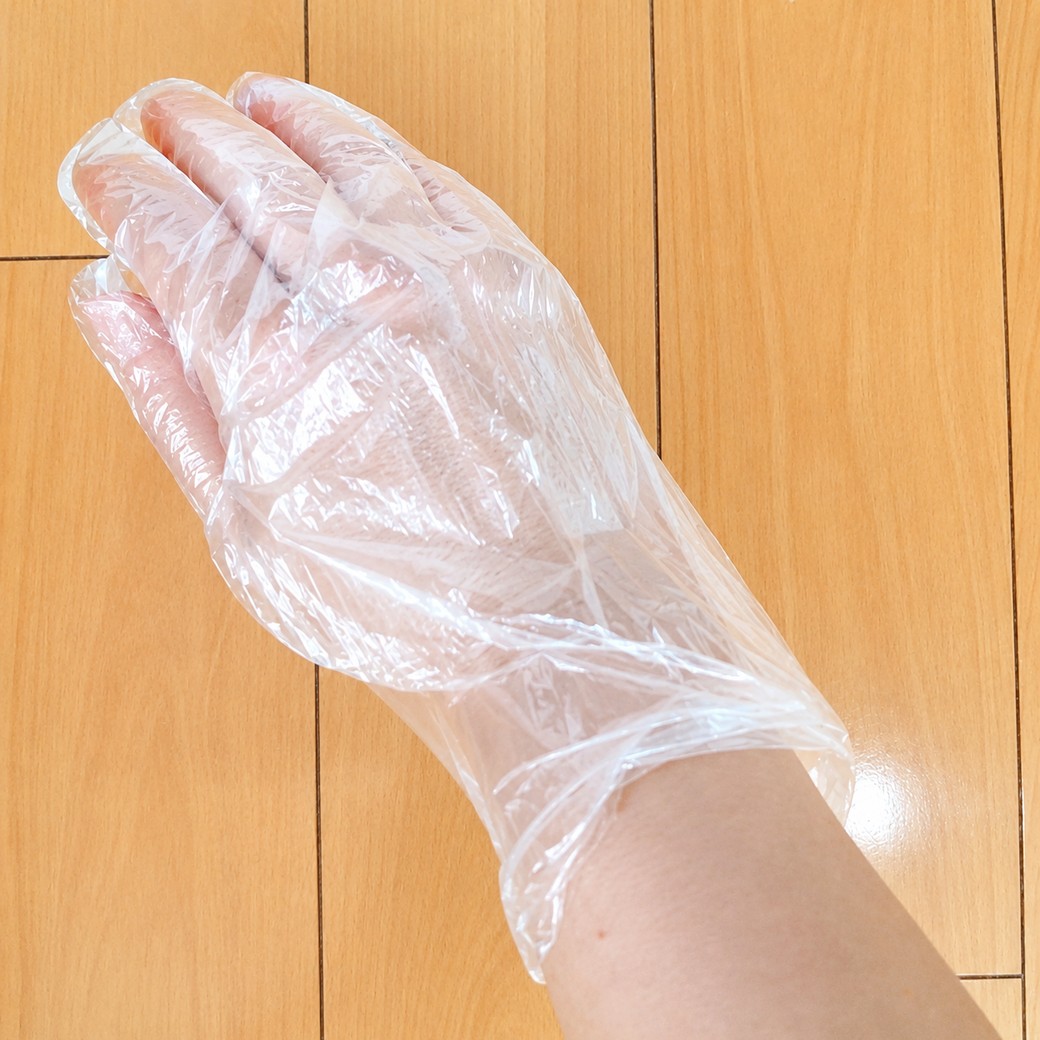 手首部分を引っ張ったビニール手袋をつけている人