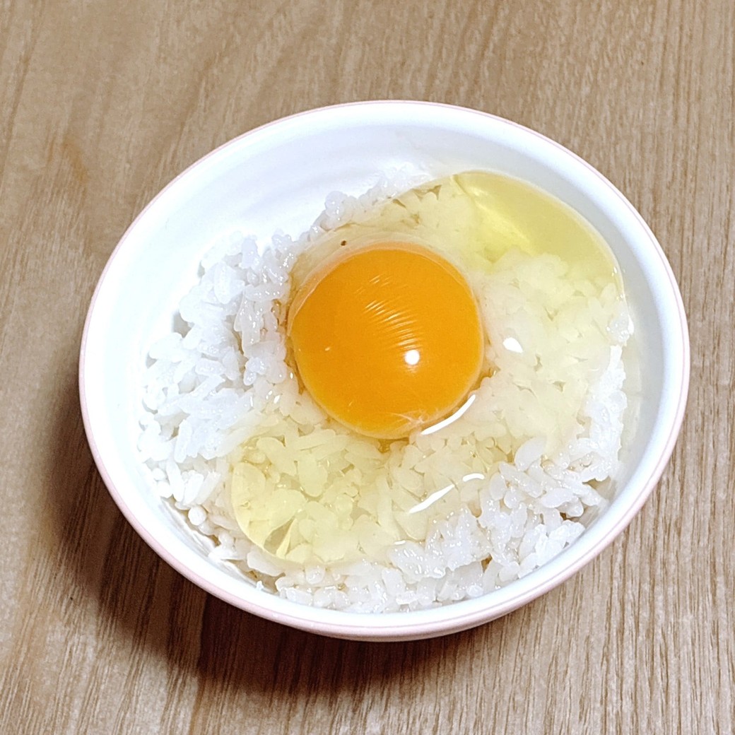 ごはんに卵を割り入れる