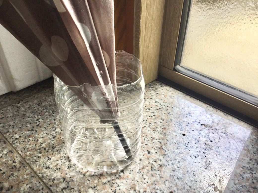 濡れた傘の先端をペットボトルに入れる