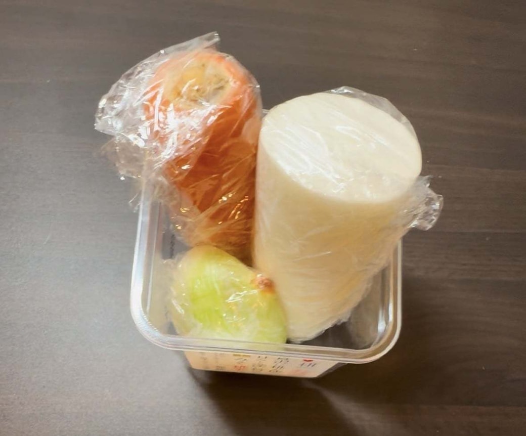 ラップで包んだ使いかけ野菜をみその空き容器に入れている様子