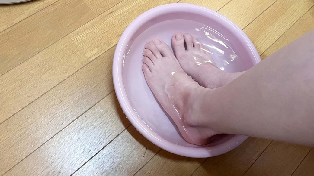 洗面器に冷水を入れて足を冷やす様子